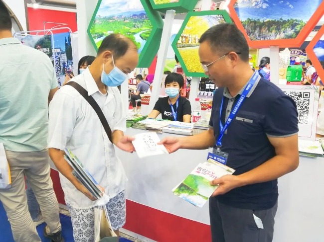 图为我县文广旅体局局长邬国锋派送旅游宣传手册